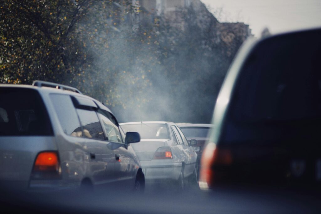 City traffic jam with cars emitting smoke on a busy road.